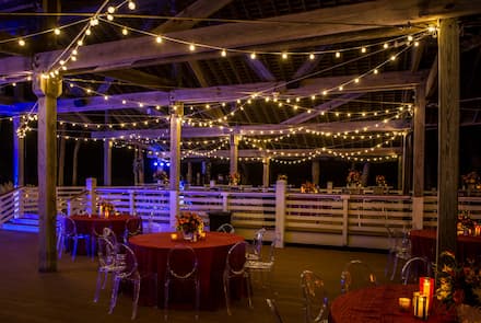 Night view of a wedding setup with string lights in an outdoor pavilion.