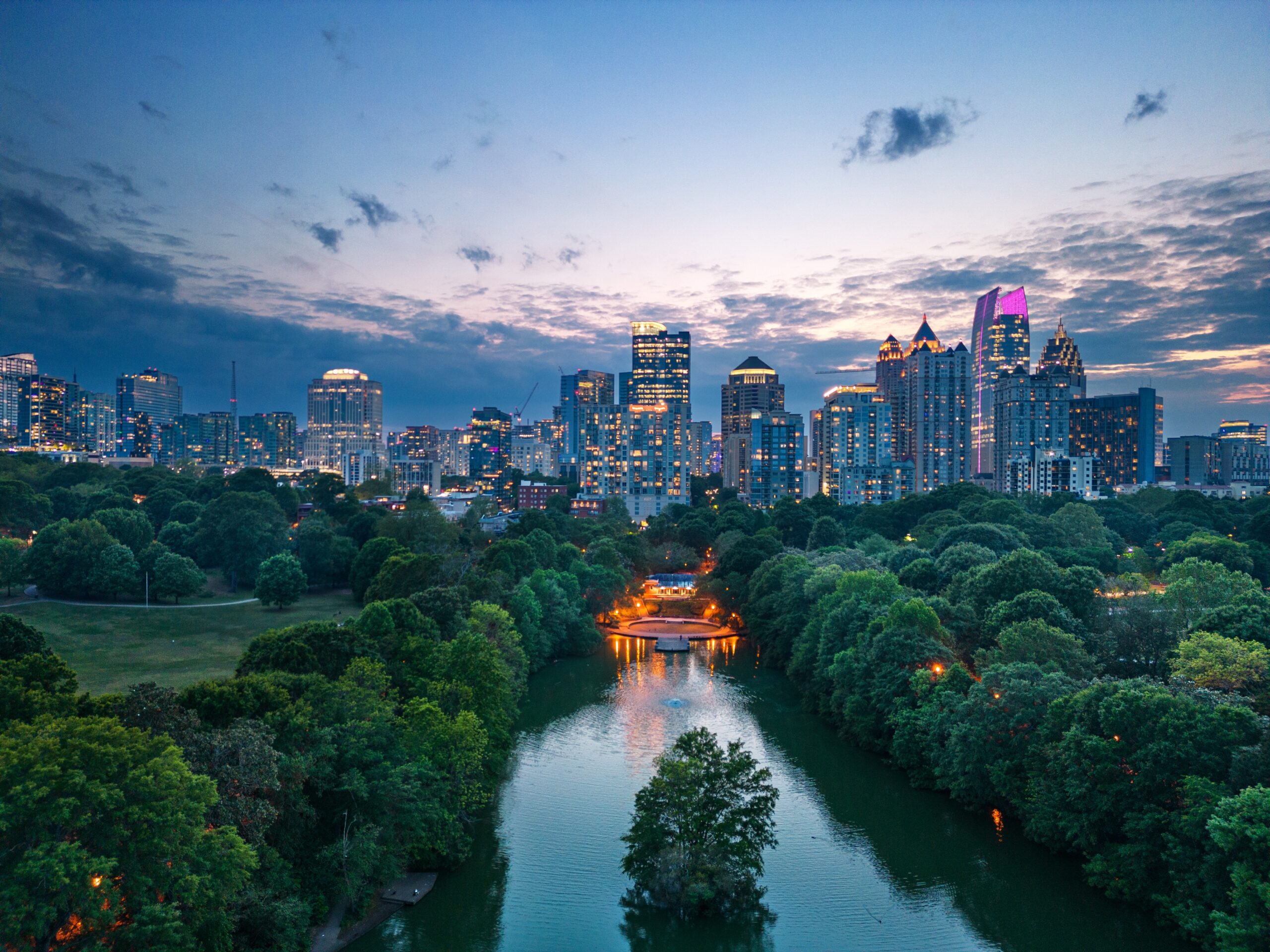 View of the skyline at sunset with shrubbery and a lake.