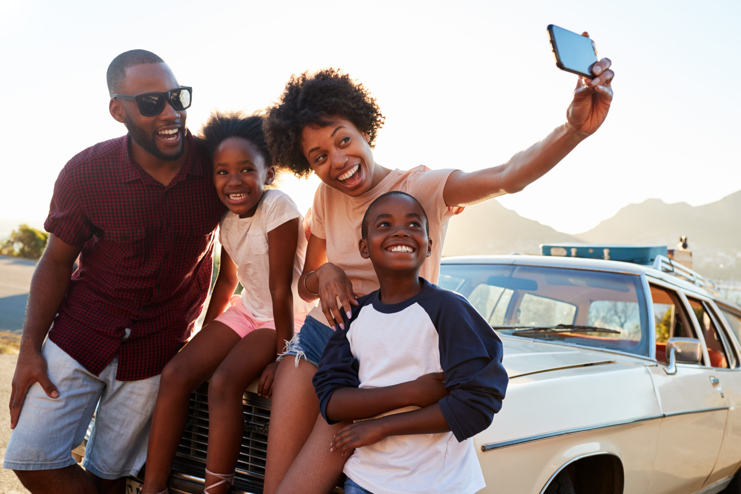 Image with family posing for selfie next to a car