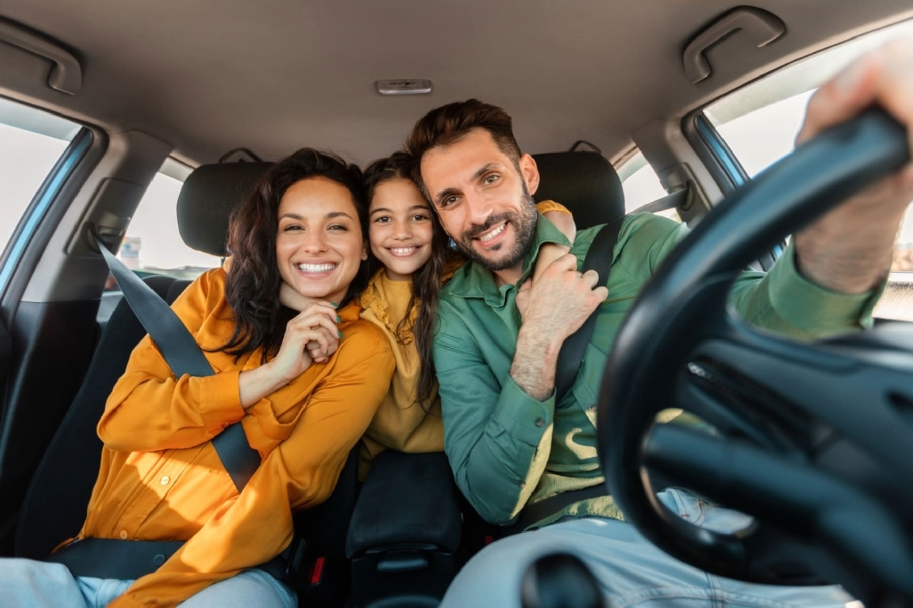 Image of a family in the car smiling for the photo