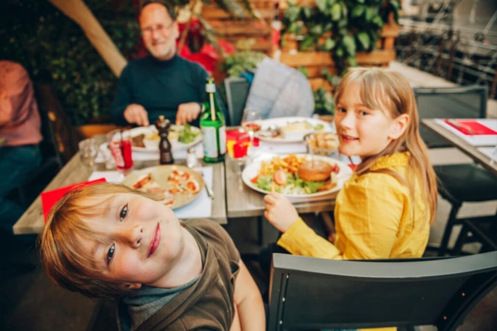image of a family eating while the two children are turned around looking at the camera for the photo.
