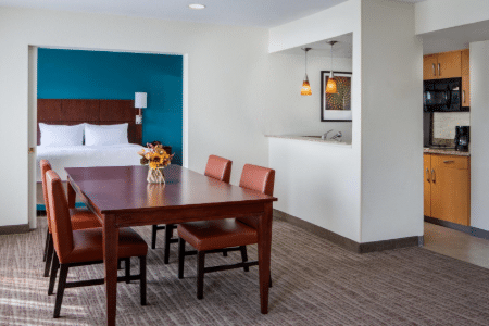 view of hotel room with separate bedroom, dining room and kitchen.