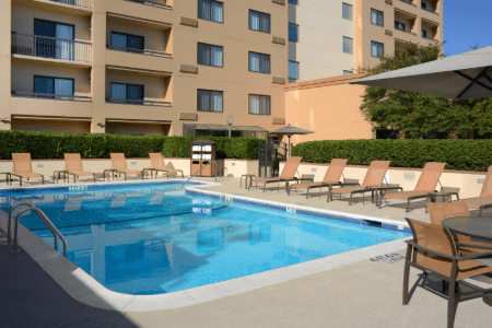 View of hotel outdoor pool with tanning chairs.