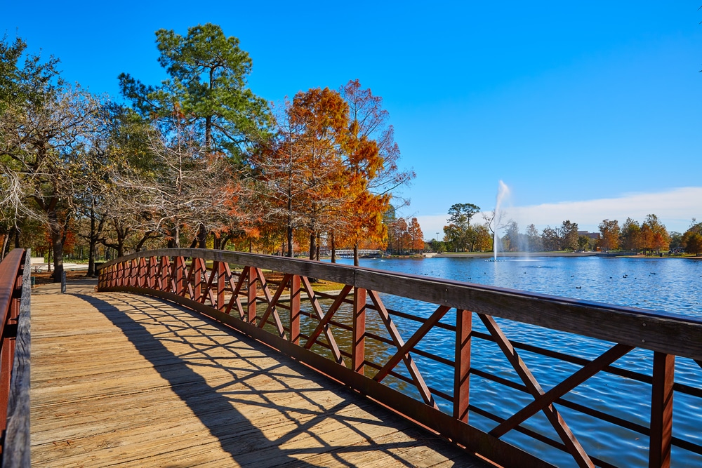A wooden footbridge leads across McGovern Lake in Hermann Park, one of Houston’s most family-friendly parks.