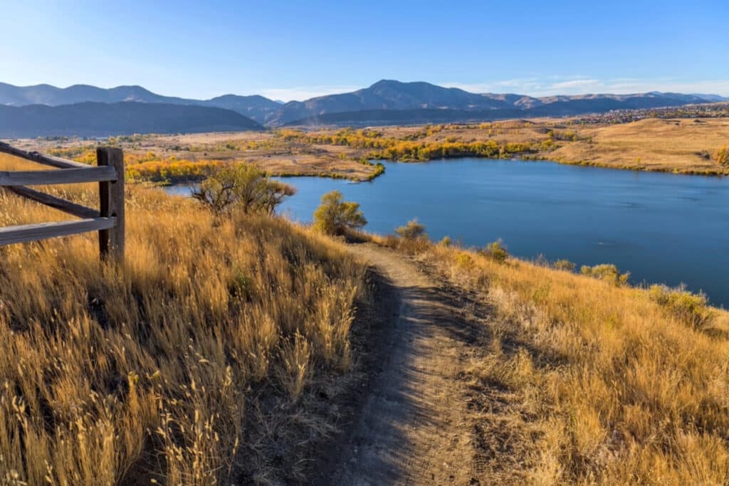 View of a trail through a field with the lake on the right hand side.