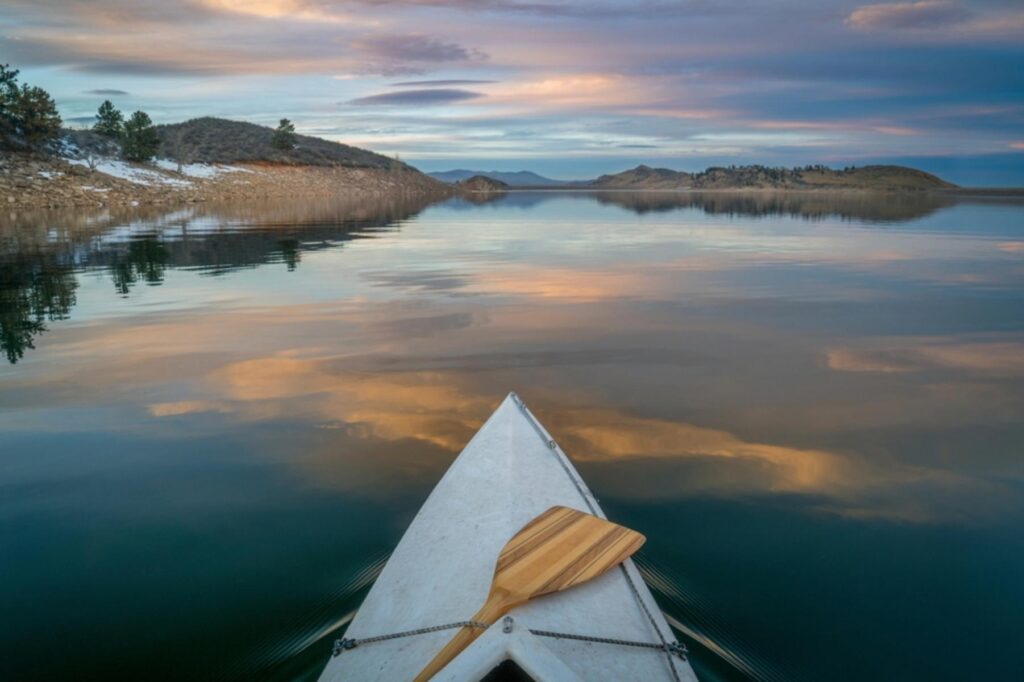 view of a canoe on clear water at sunset.