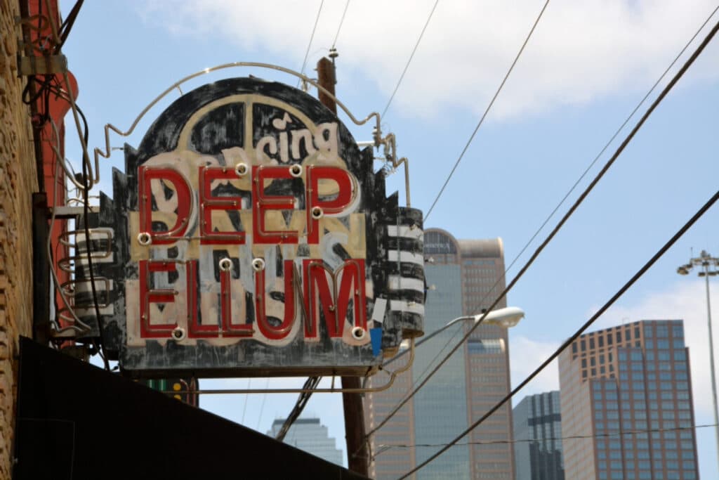 Photo taken of The Deep Ellum Sign with the city in the background.