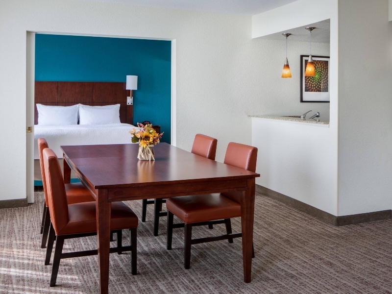 View of the hotel room with a dining table, kitchen and separate bedroom.