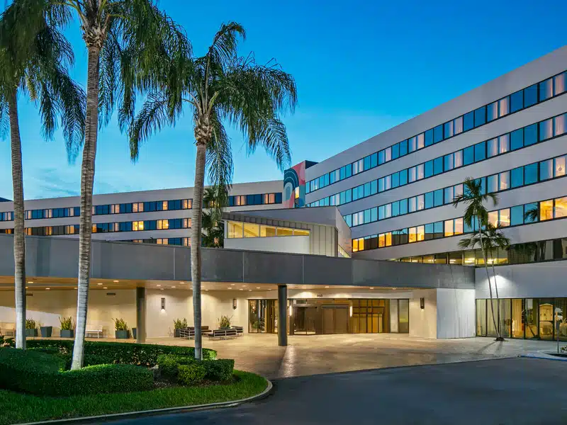 External view of the Miami airport hotel with palm trees in front.