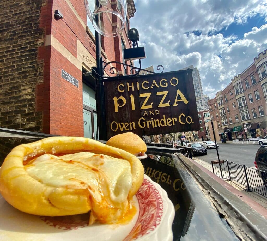 A plate of food on a table, with a Chicago pizza sign in the background, highlighting the local cuisine.