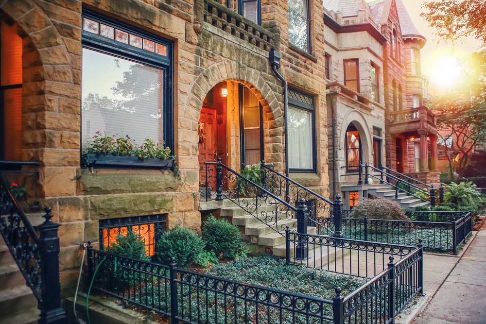 A row of brick houses with steps, illuminated by a warm sunset in the background.