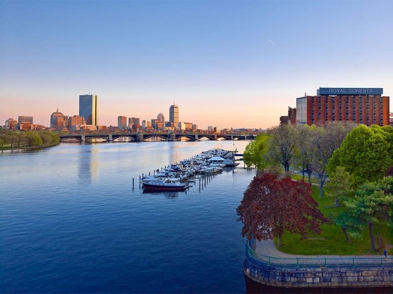 A panoramic view of the city skyline from a bridge, showcasing tall buildings against a clear blue sky.