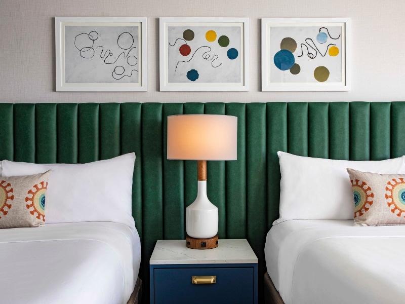 View of two queen size beds side by side with a lamp in the middle
