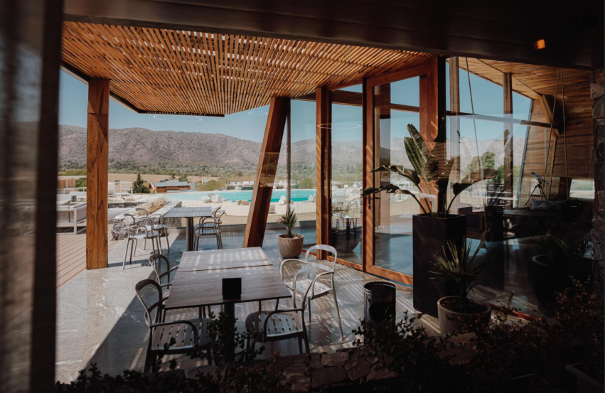 View from inside the house showcasing the patio and pool area, surrounded by greenery and sunlight.