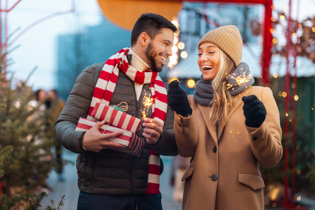 A couple gazes at each other while holding sparklers, creating a romantic and festive atmosphere.