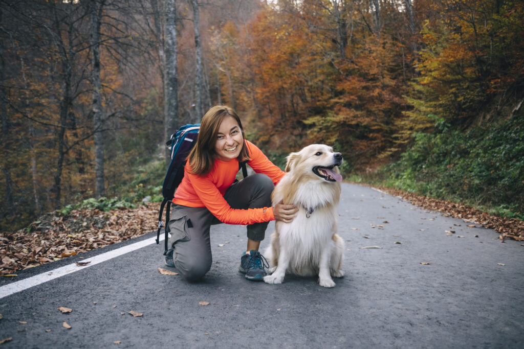 Smiling woman kneeling with dog on road