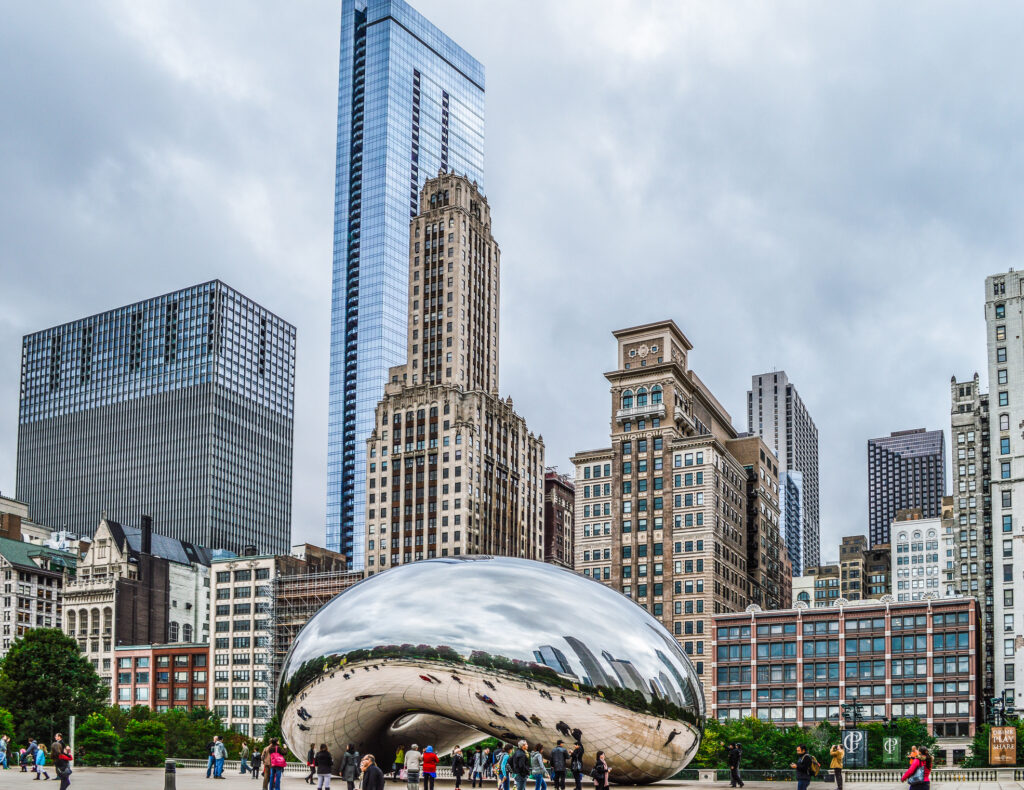 A large bean sculpture stands in the foreground against a backdrop of a cloudy sky.
