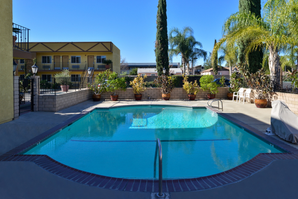 A serene courtyard featuring a swimming pool surrounded by palm trees and a cozy patio area for relaxation.
