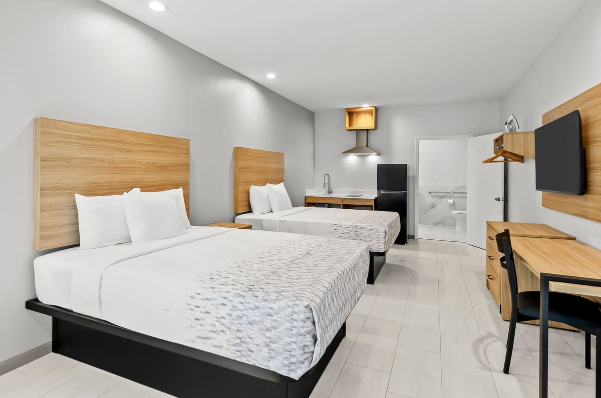 A hotel room featuring two beds, a television, and neutral-colored walls, creating a cozy atmosphere.