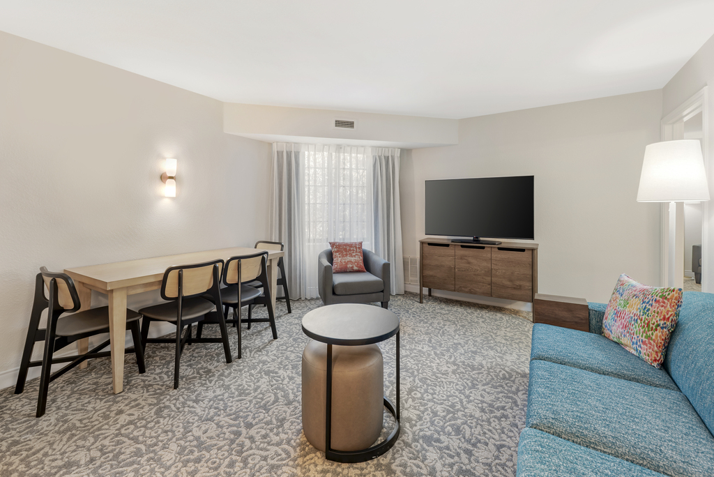 A hotel room featuring a couch, a table, and a television, creating a comfortable and inviting atmosphere.