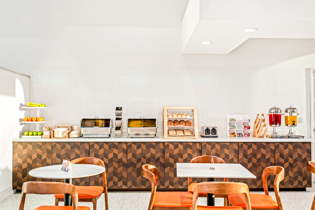 A breakfast area featuring orange chairs and a sleek counter, creating a vibrant and inviting atmosphere.