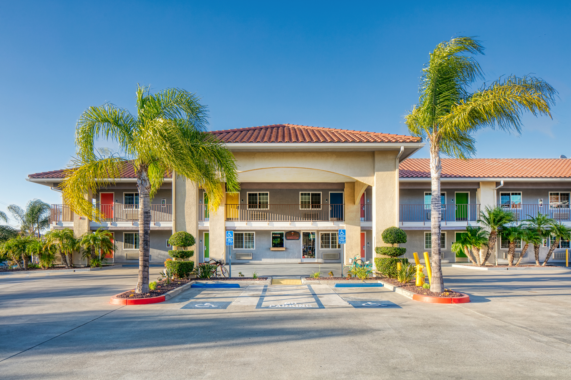 Front entrance of a hotel surrounded by palm trees, showcasing a welcoming atmosphere and tropical ambiance.