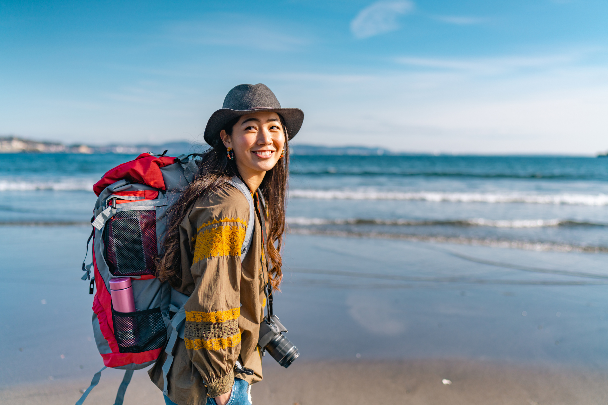 A young female traveller is enjoying spending time at the beach on her vacation.