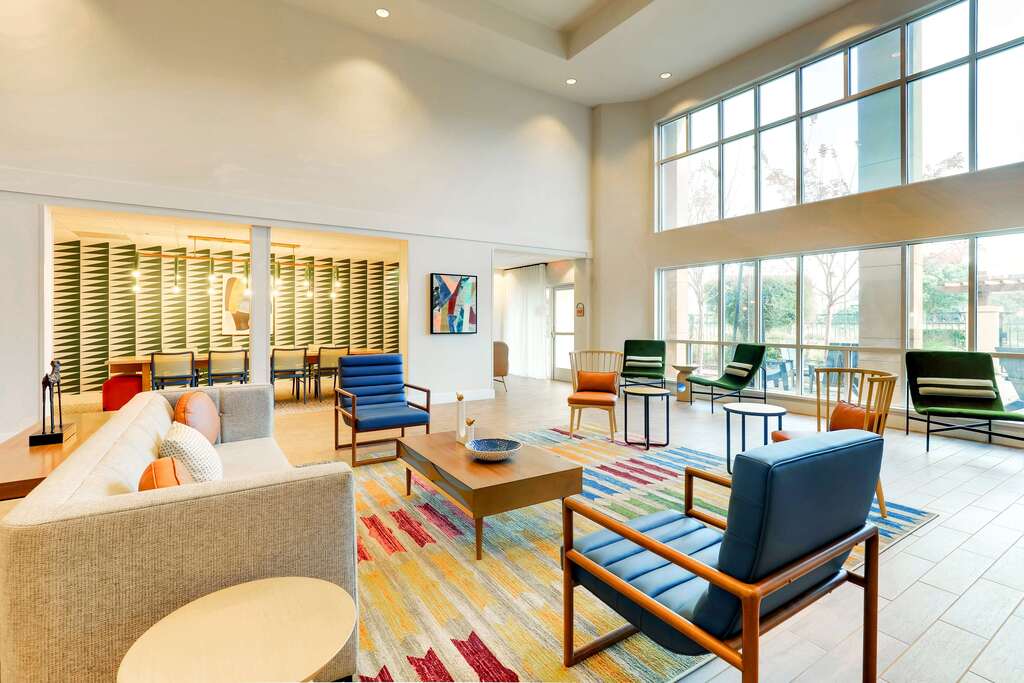 A spacious hotel lobby showcasing stylish seating, natural light, and contemporary decor.