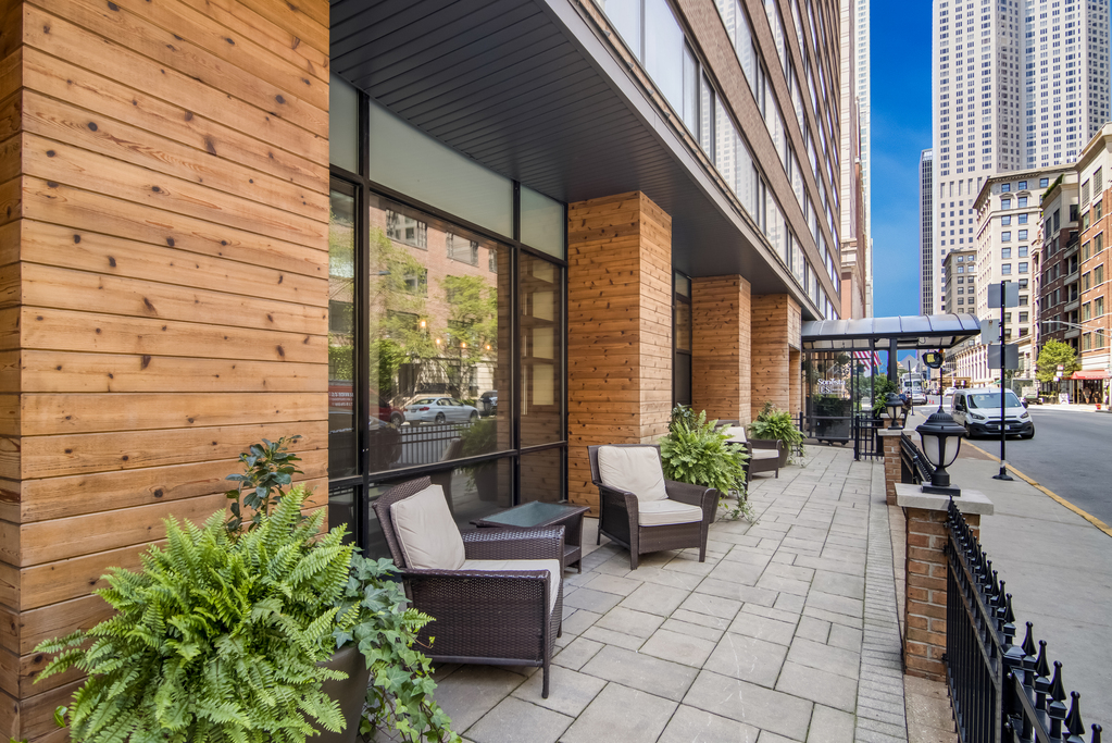 A sidewalk patio adorned with chairs and lush greenery in potted plants.