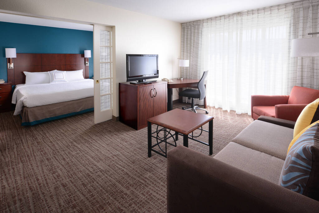 A well-furnished hotel room with a cozy bed, a desk for work, and a television for leisure activities.