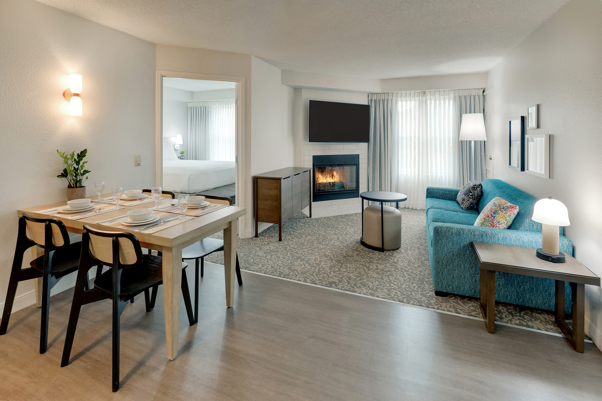 A cozy airport guest room featuring a couch, table, and a fireplace for a comfortable stay.