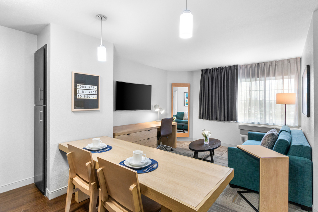 A modern hotel room featuring a dining table and a comfortable couch, showcasing contemporary decor and spacious layout.