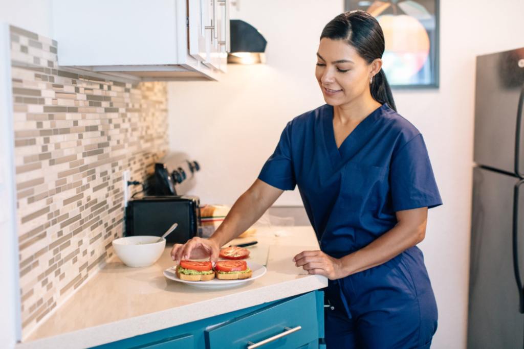 A woman dressed in a blue uniform is actively preparing meals in a culinary environment.