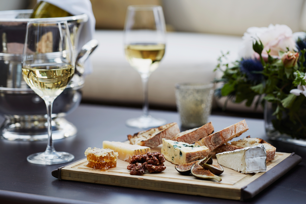 A table set with wine glasses and an assortment of cheeses, creating an inviting atmosphere for a gathering.