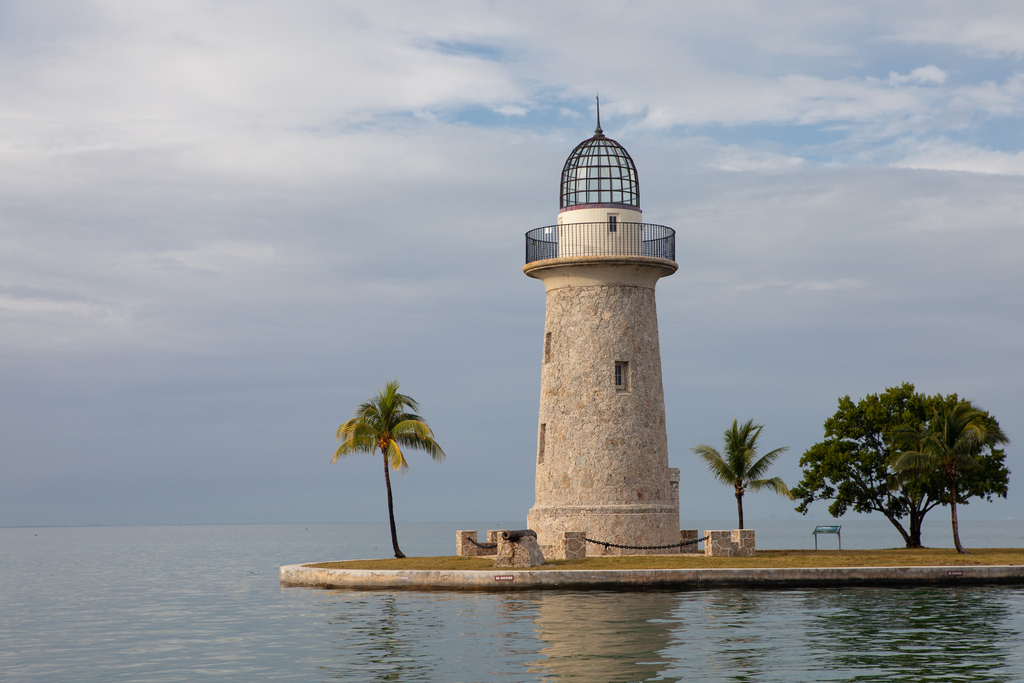 A solitary lighthouse perched on a small island, with waves gently lapping at its rocky shore.