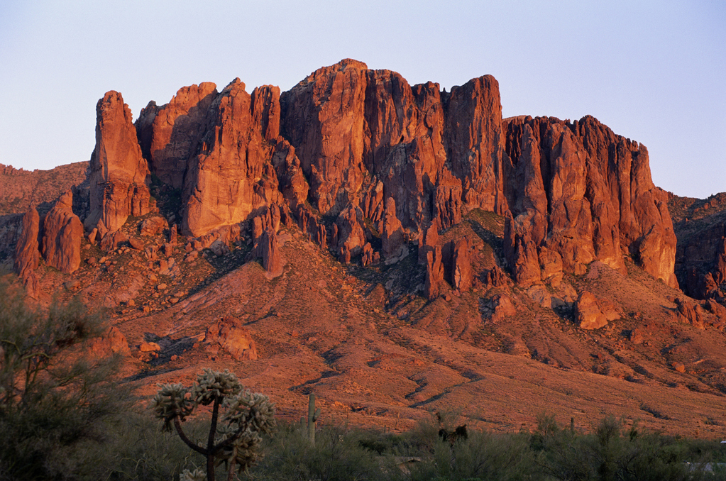 Red mountains under a clear blue sky, showcasing vibrant hues and rugged terrain.