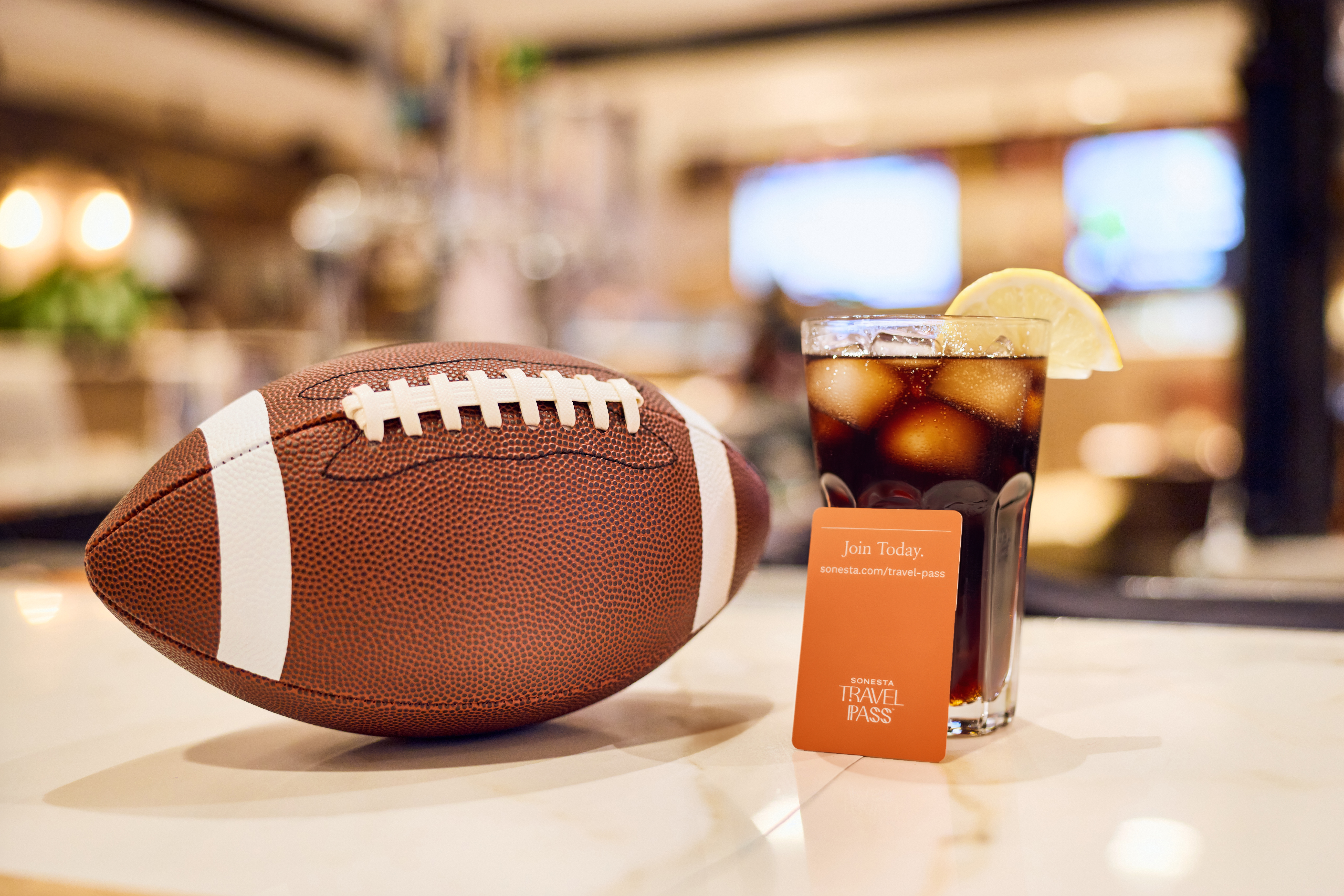 A glass of Coca Cola and a rugby ball are placed on the table.