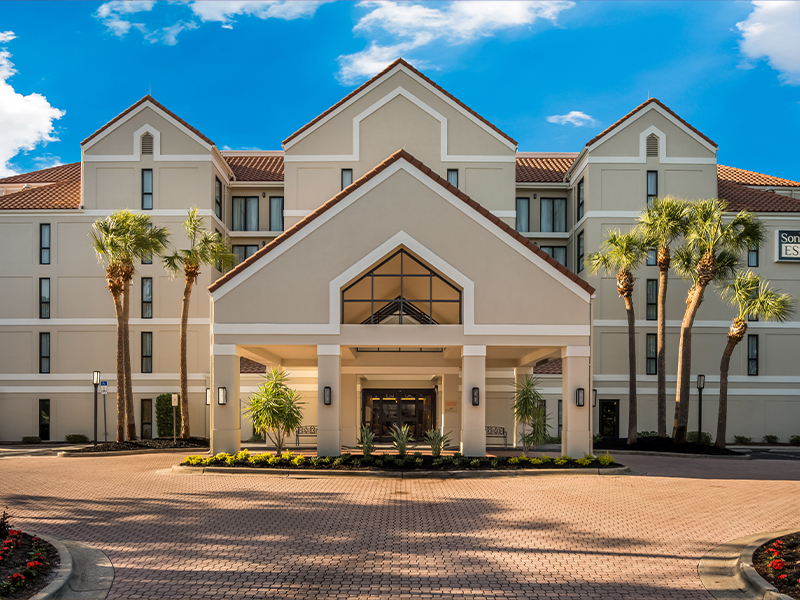 Exterior view of the hotel highlighting the main entrance with a covered walkway and bright signage.