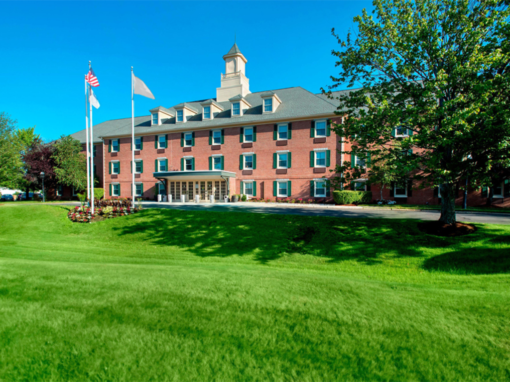 A cozy welcoming entrance, surrounded by lush greenery and a clear blue sky.
