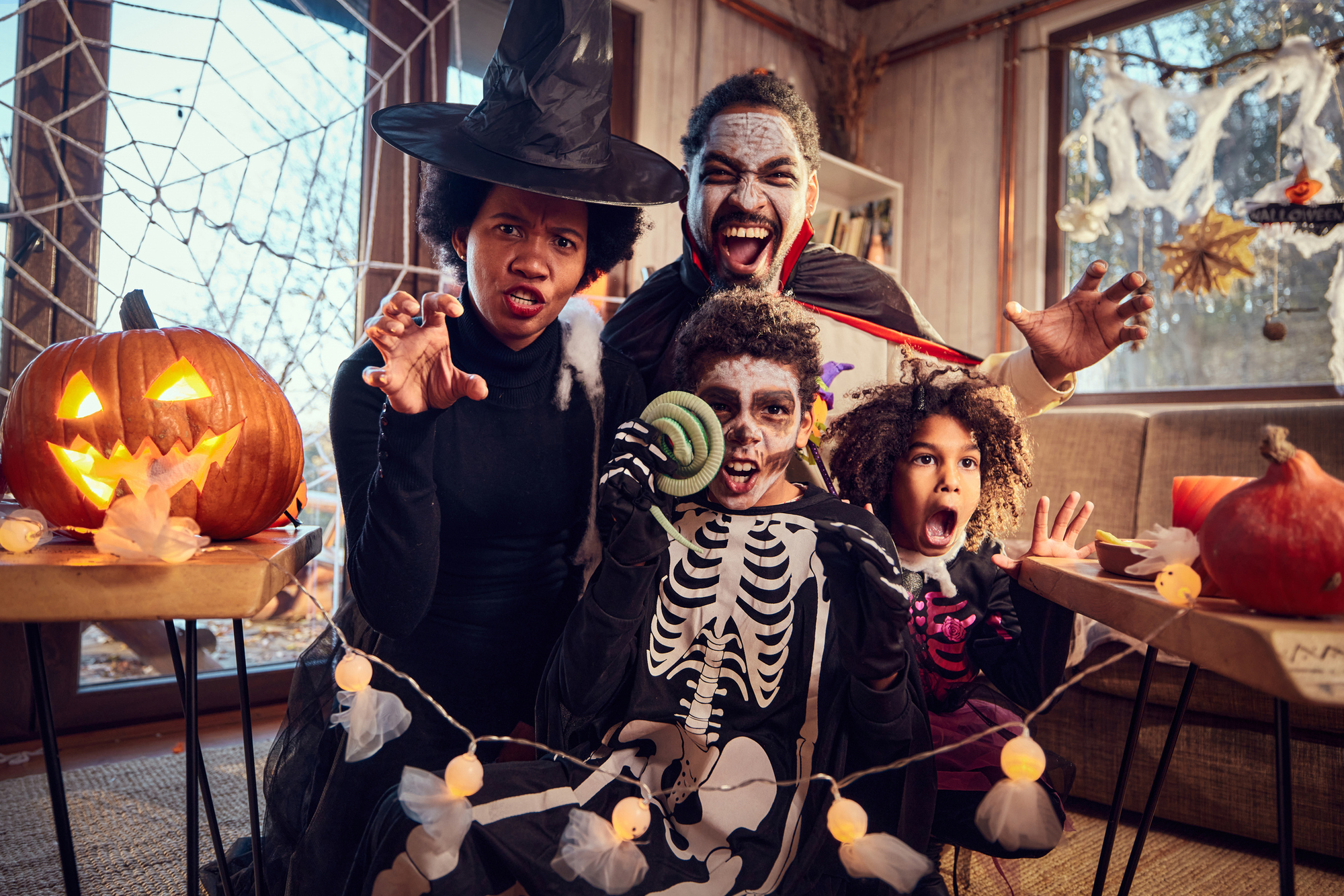 A family poses together in colorful Halloween costumes, showcasing a variety of characters and festive accessories.