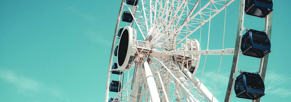 A towering ferris wheel is set against a bright blue sky, highlighting its vibrant colors and intricate design.