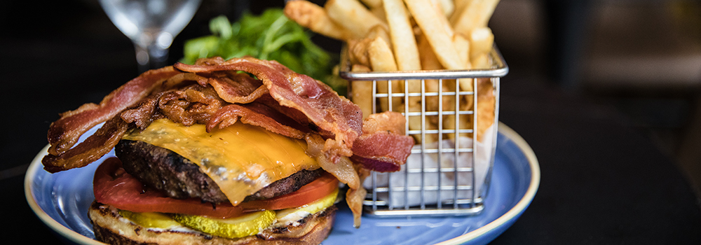 A close-up of a burger featuring layers of bacon and cheese, showcasing its appetizing ingredients.