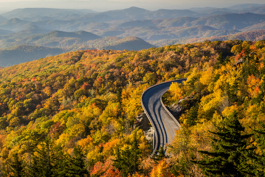 Scenic view of the Blue Ridge Parkway in autumn, showcasing vibrant fall foliage and rolling hills under a clear sky.