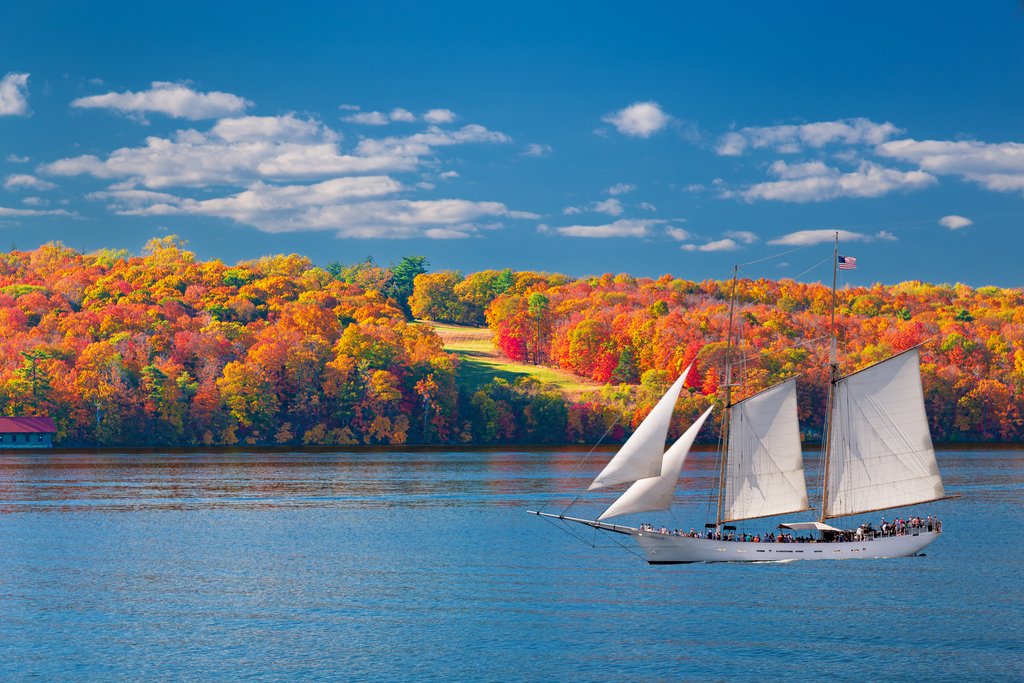 A sailboat gliding across calm water under a clear blue sky.