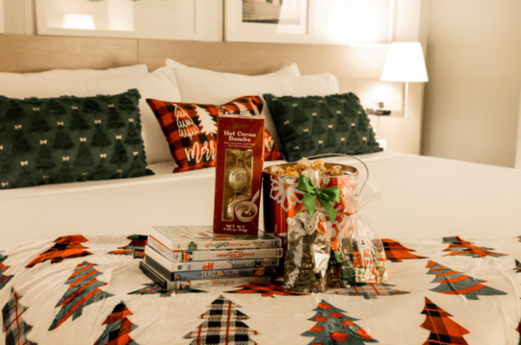 A bed adorned with a Christmas tree patterned blanket, featuring several books neatly arranged on top.