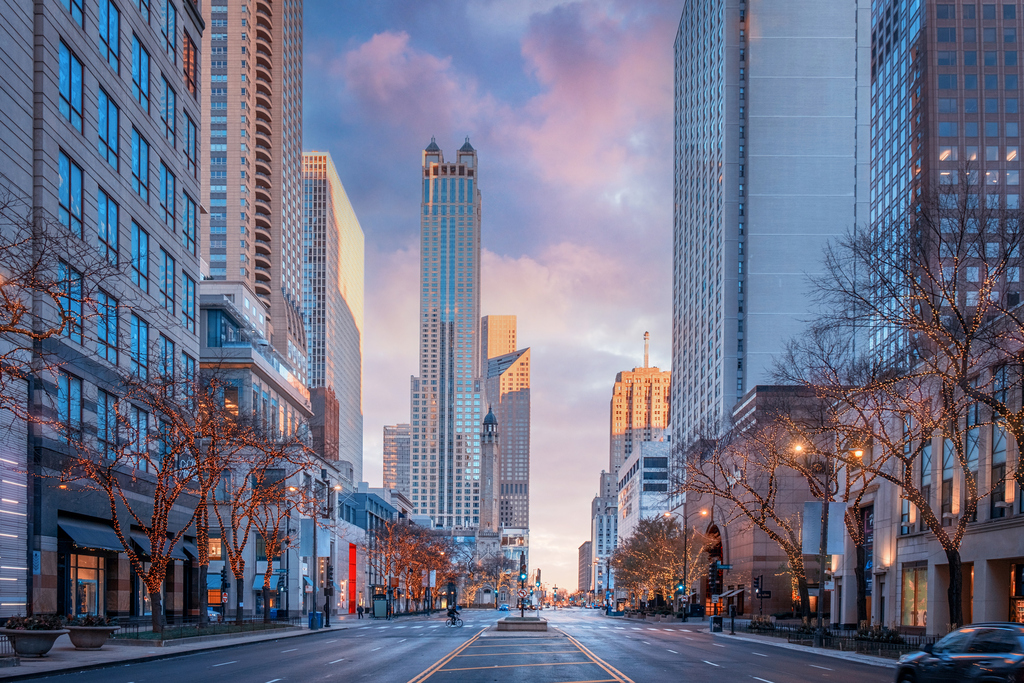 A bustling city street lined with tall buildings and parked cars, showcasing urban life and architecture.