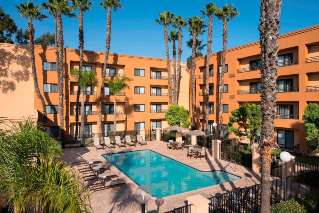 A serene courtyard pool surrounded by palm trees and lounge chairs.