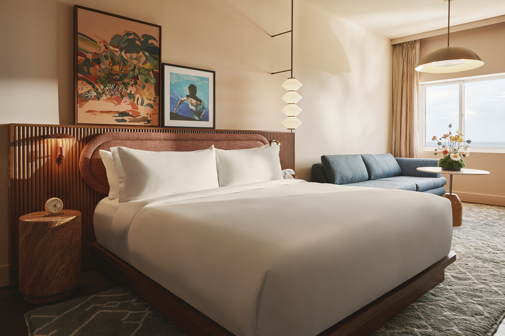 A hotel room featuring a bed, a couch, and a large window allowing natural light to enter the space.