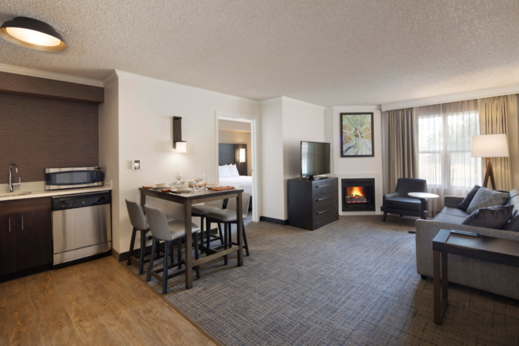 A spacious hotel room featuring a kitchen, living area, and dining area, designed for comfort and convenience.