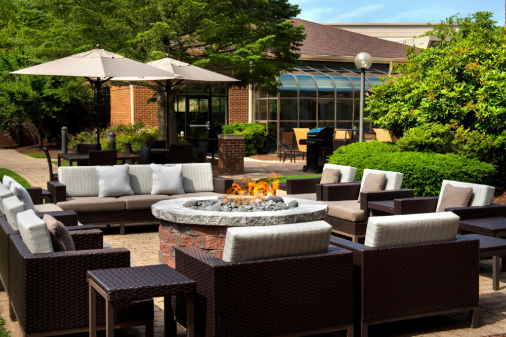 A cozy patio featuring wicker furniture arranged around a warm outdoor fire pit, ideal for gatherings.